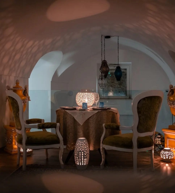 Tavolo per cena romantica in ambiente interno con luci soffuse e atmosfera intima