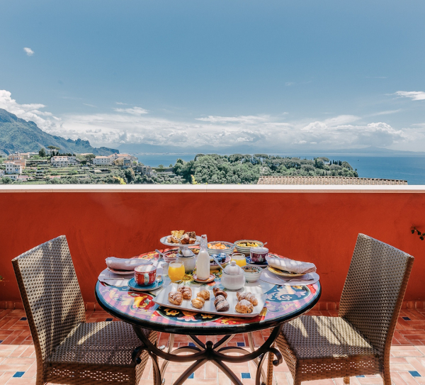 Tavolo apparecchiato per colazione con vista mare sulla Costiera Amalfitana in un contesto esclusivo