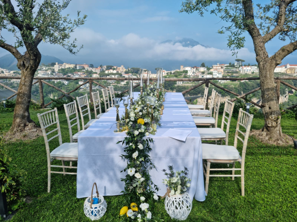 Tavola elegante allestita tra ulivi con vista sulla Costiera Amalfitana per un ricevimento privato esclusivo a Palazzo Pascal